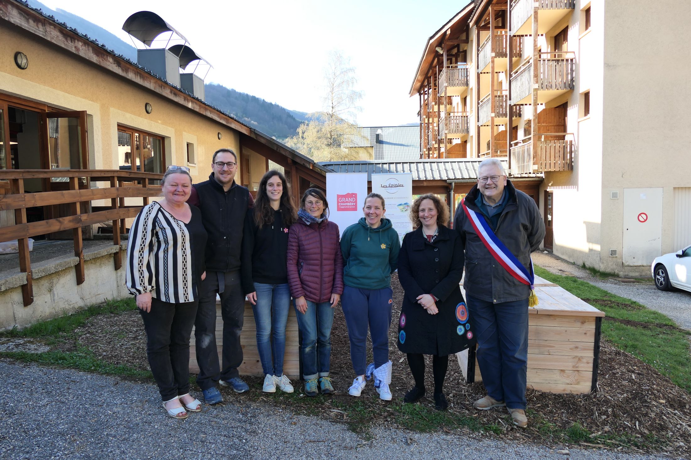 Un groupe de personnes pose devant des composteurs.