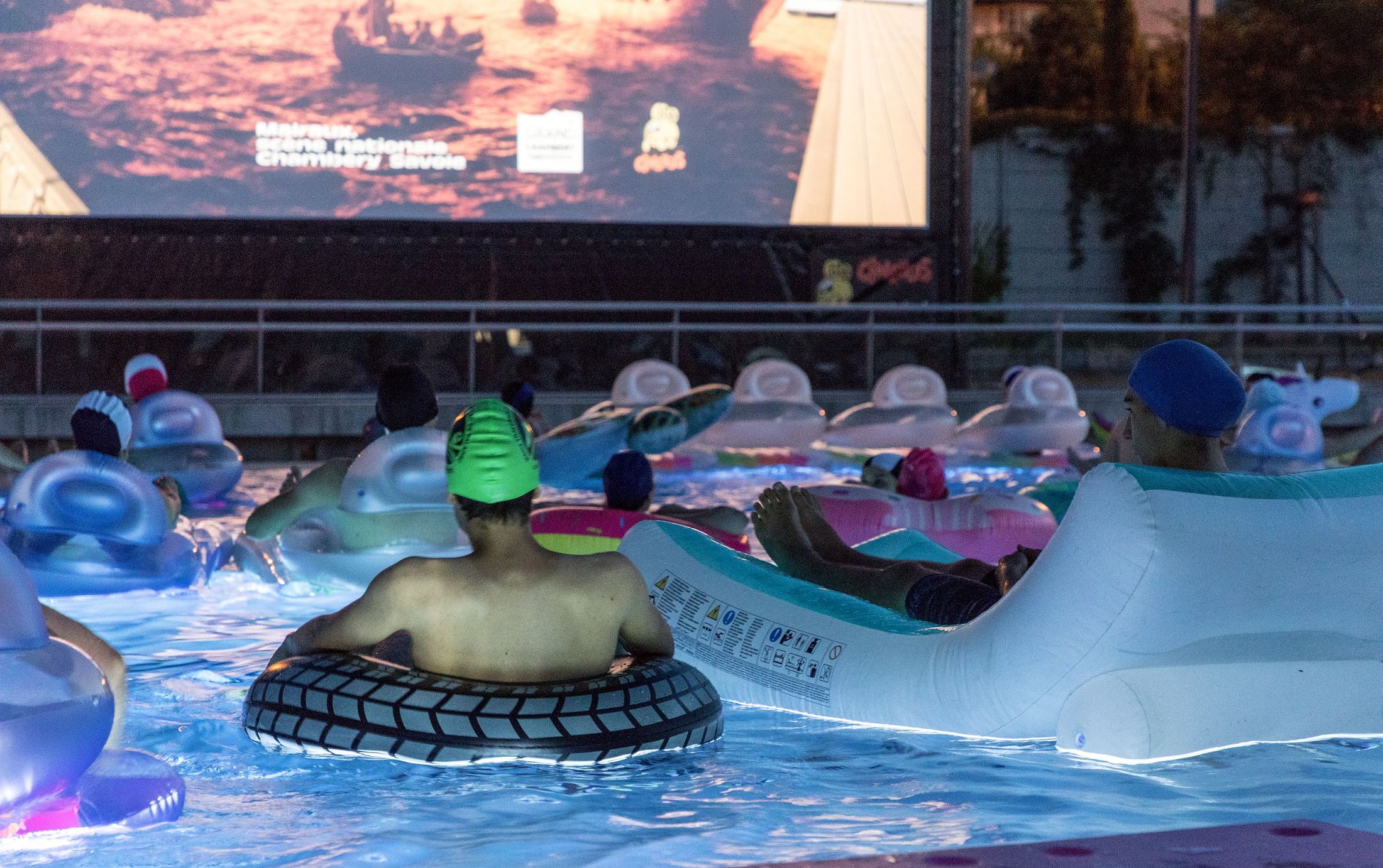 personnes sur les bouées à la piscine du Stade pour la projection du film
