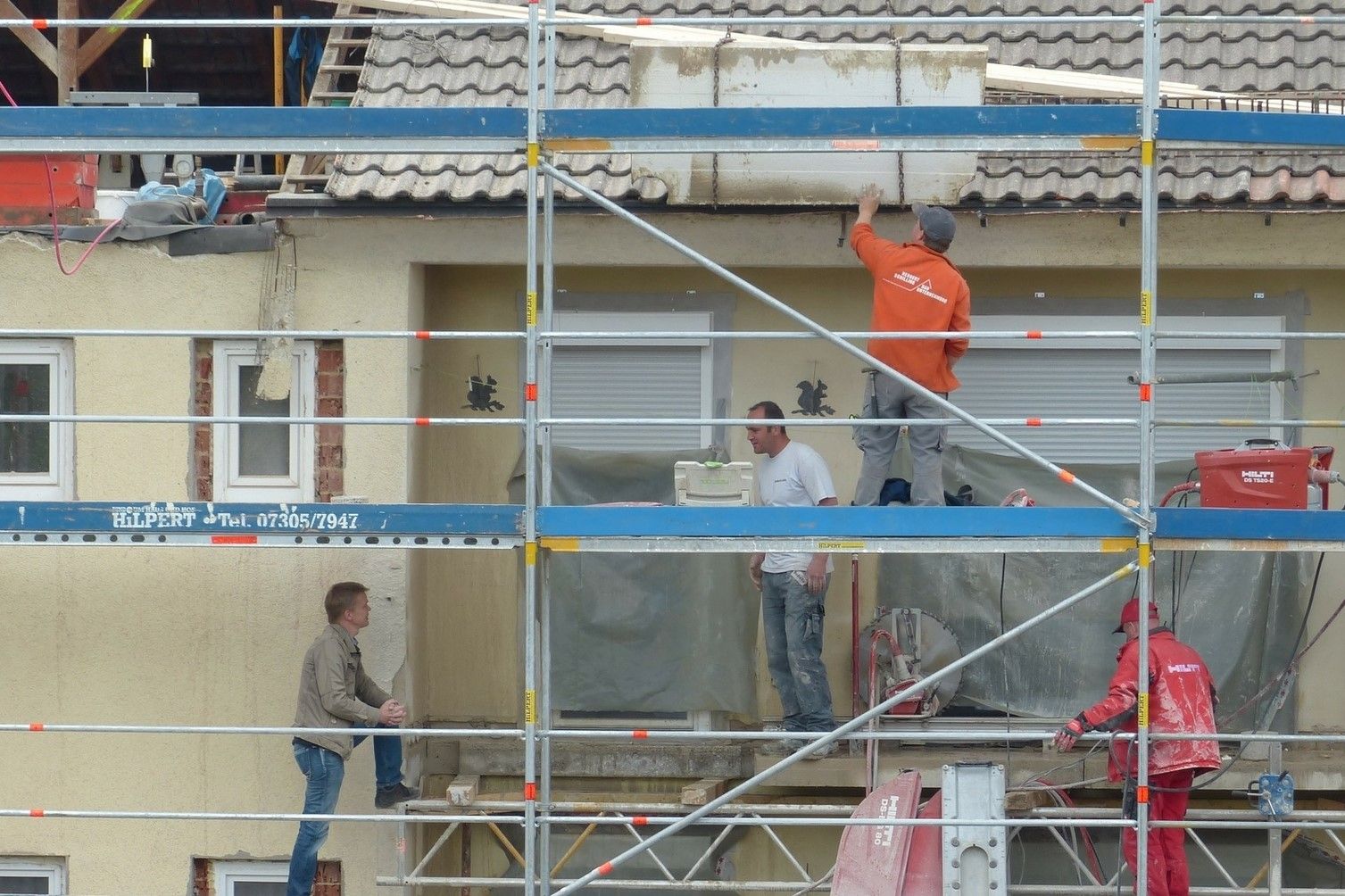 Photo de professionnels du bâtiment rénovant une façade d'une maison.