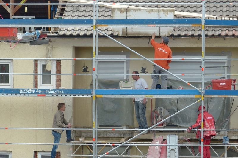 Photo de professionnels du bâtiment rénovant une façade d'une maison.