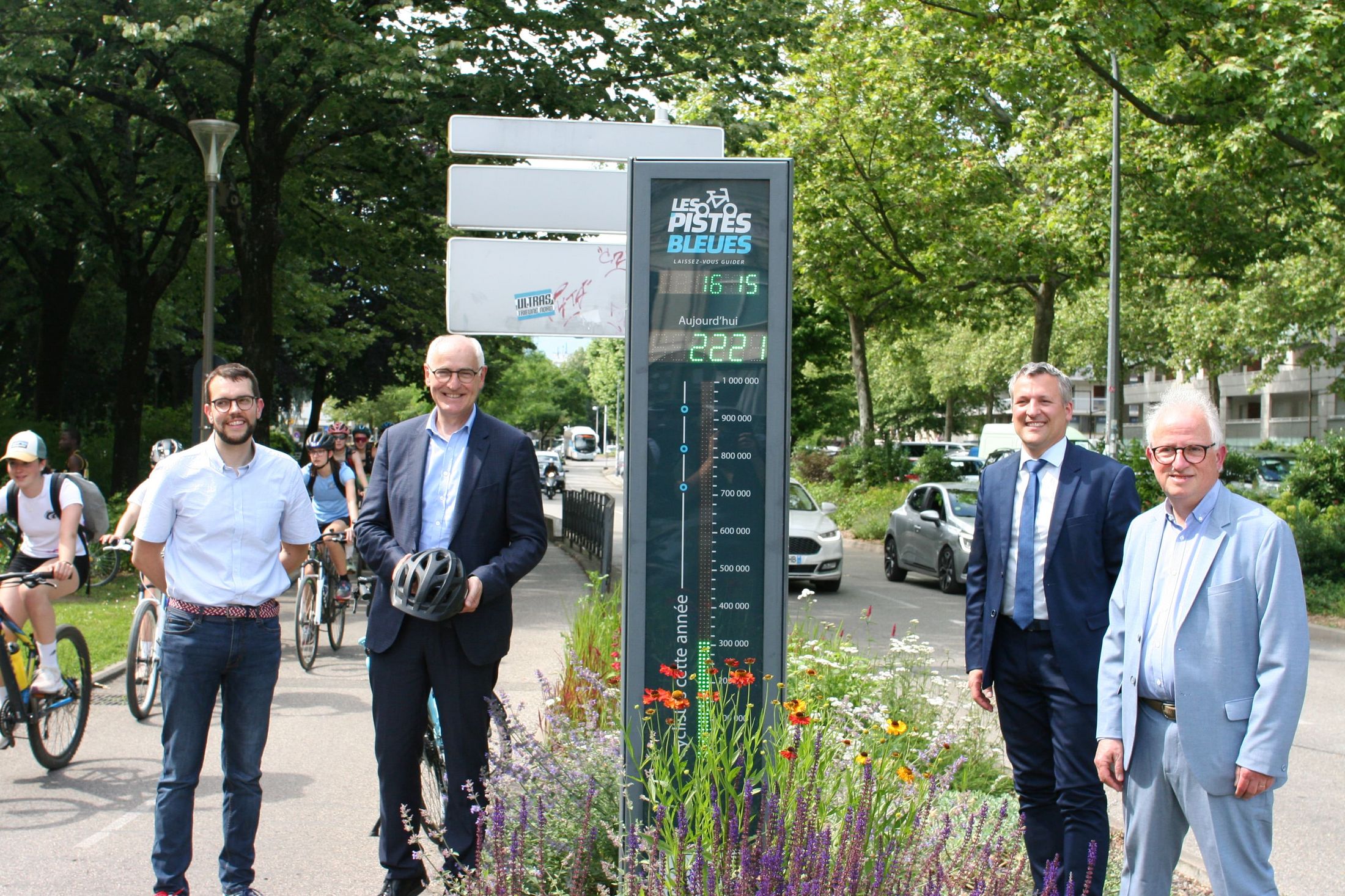 élus debout à côté d'un compteur à vélo.