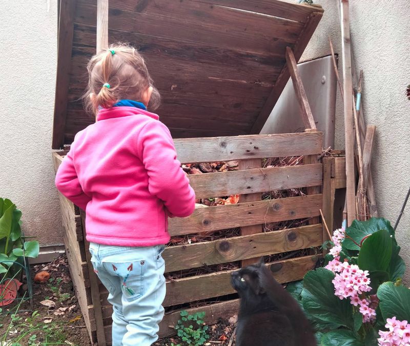 Petite fille qui se rend au compost avec son chat 