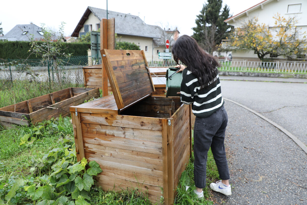 Une personne dépose des déchets dans un composteur.