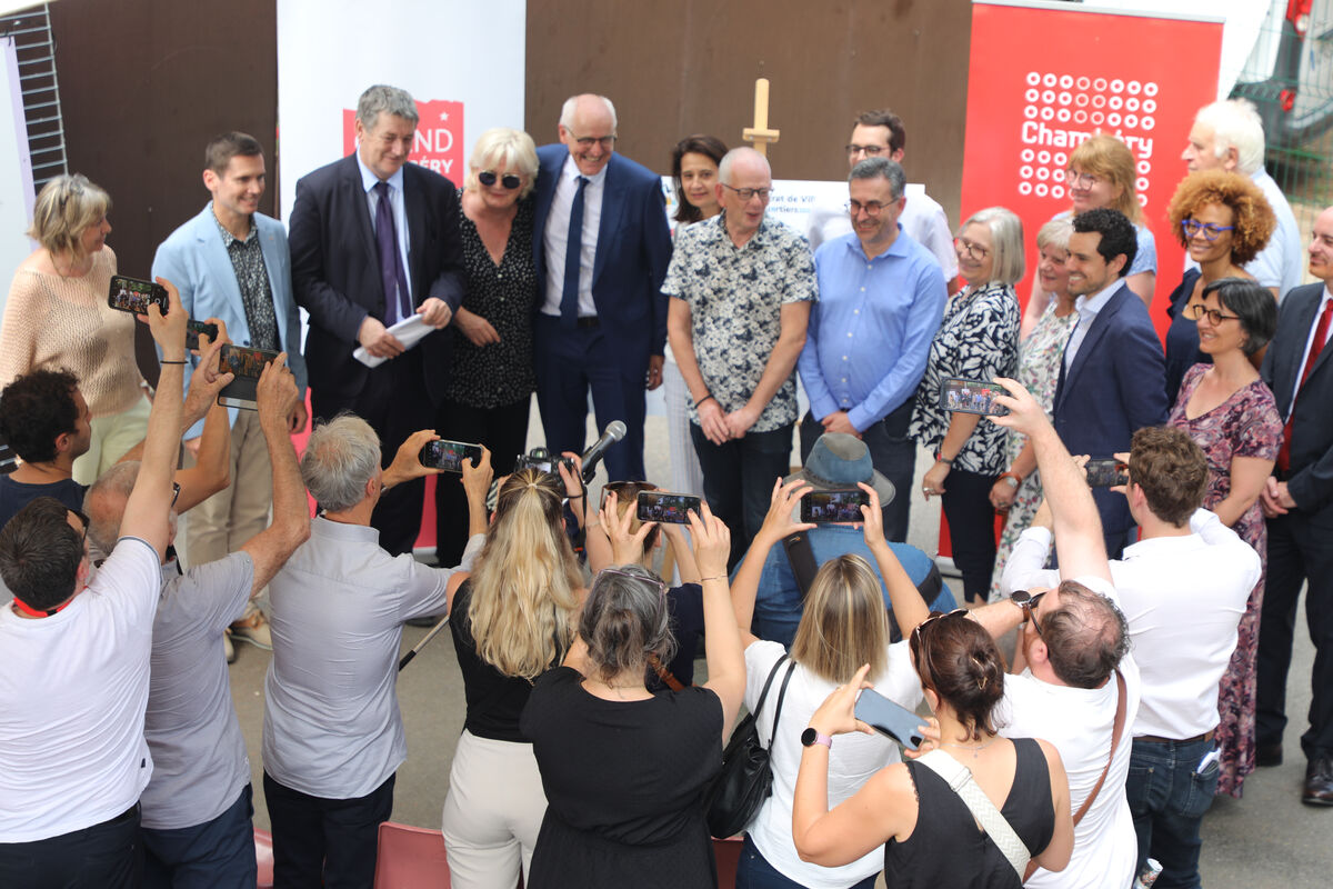 des personnes posent devant un panneau avec des signatures pendant que des personnes prennent des photos