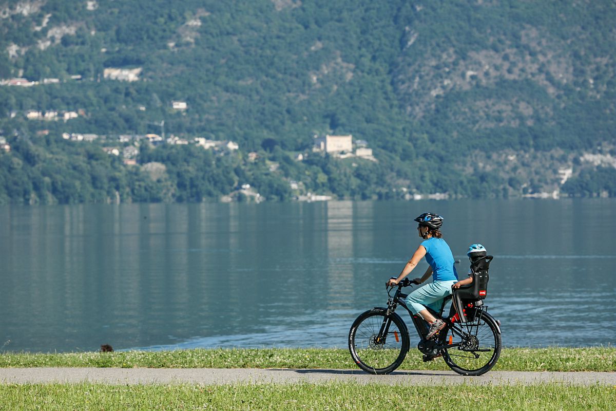 Une femme circule à vélo en transportant son enfant