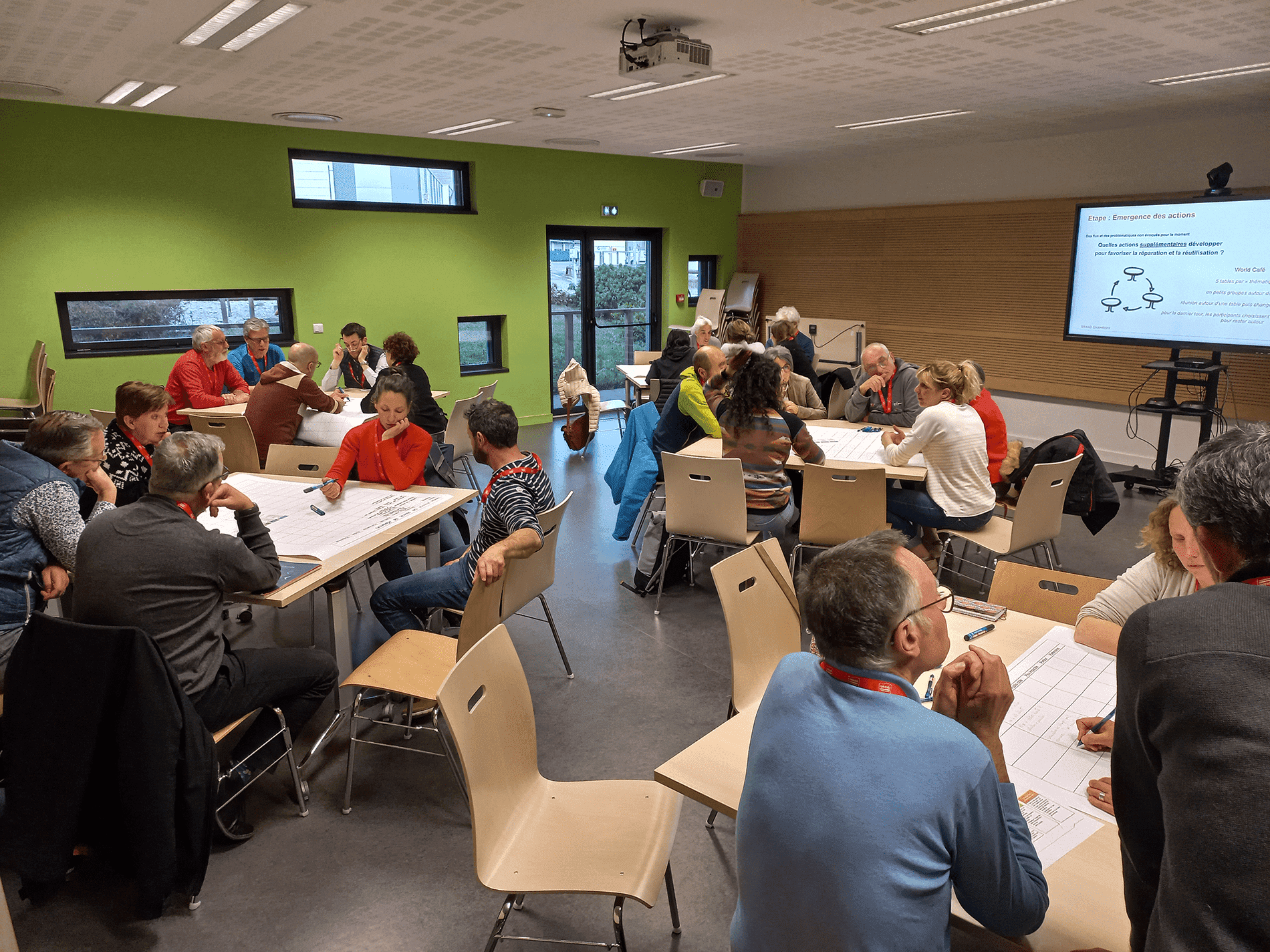 Des gens assis par petits groupes dans une grande salle.