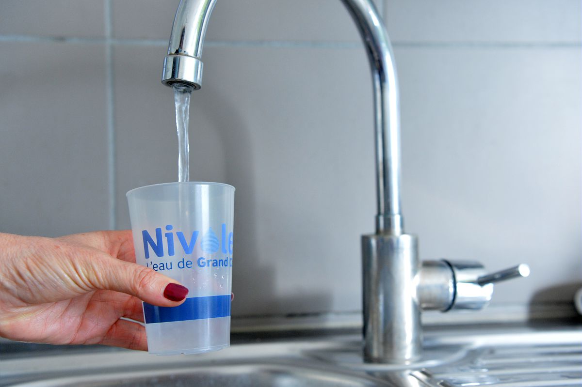 Une usagère se sert un verre d'eau du robinet.