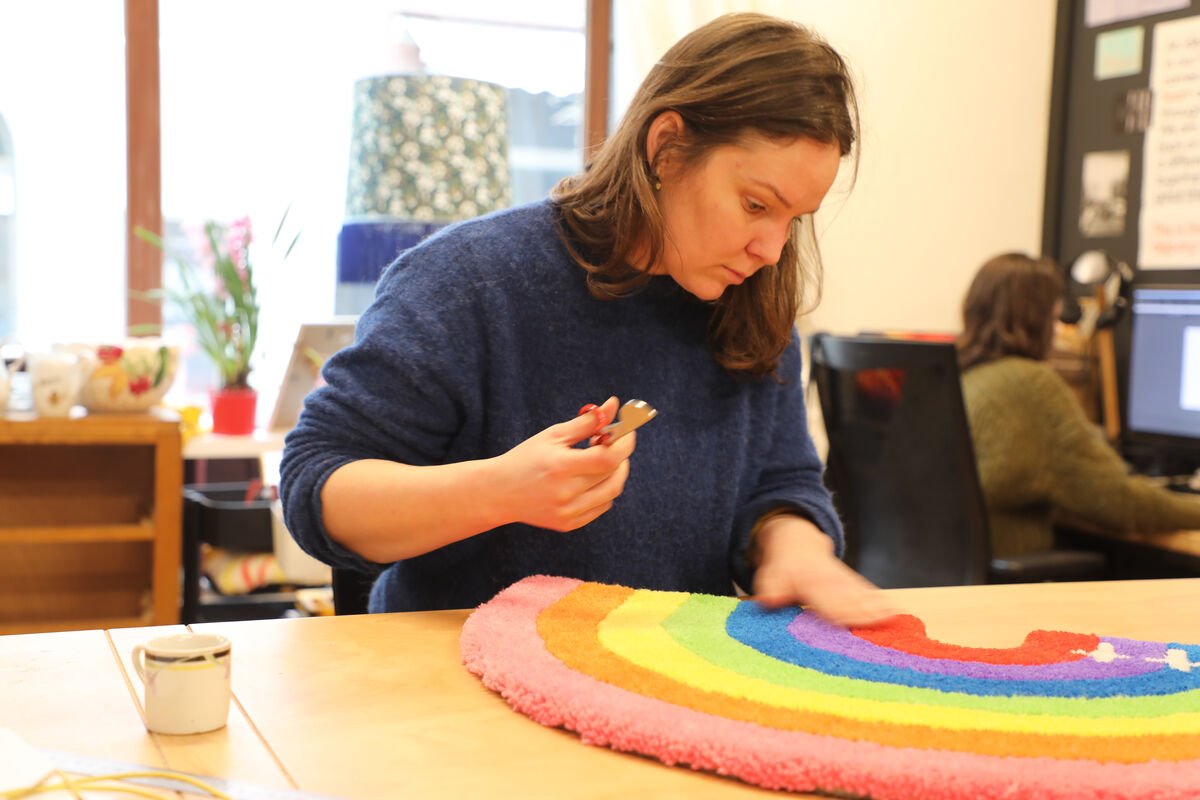 Une femme avec des ciseaux retouche un tapis