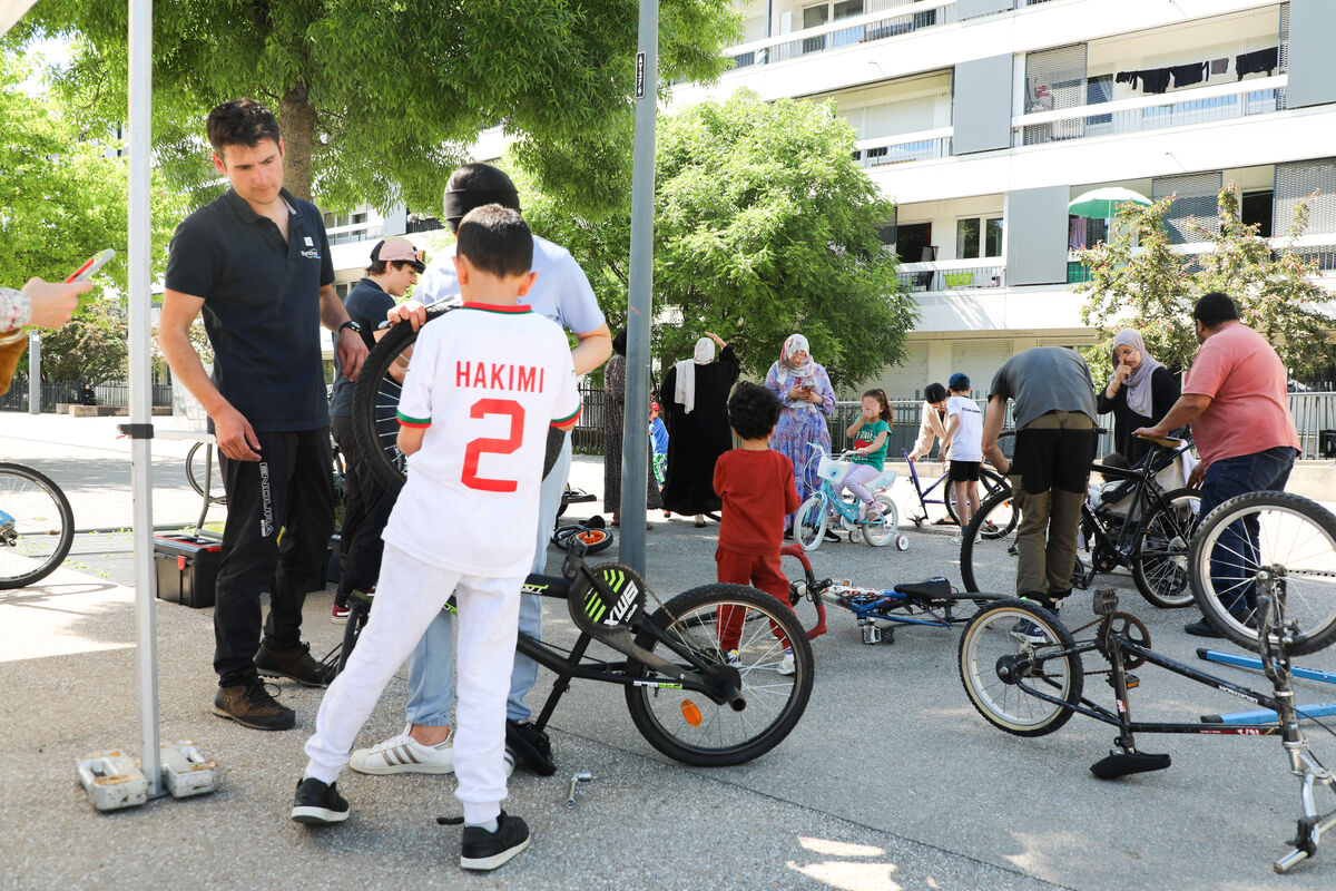 Un animateur propose un atelier d'aide à la réparation de vélo aux habitants des Hauts de Chambéry dans le cadre des ateliers de mobilité solidaire.