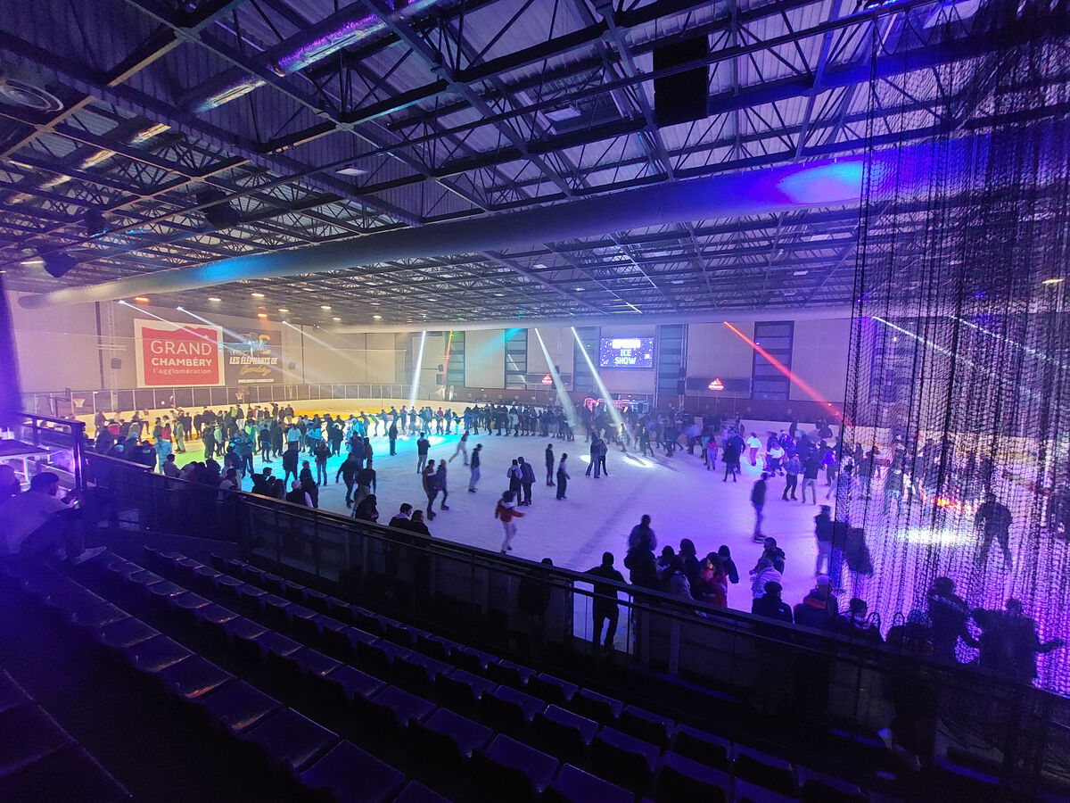 Patinoire et patineurs éclairés sous un jeu de lumières lors d'une soirée à thème. 