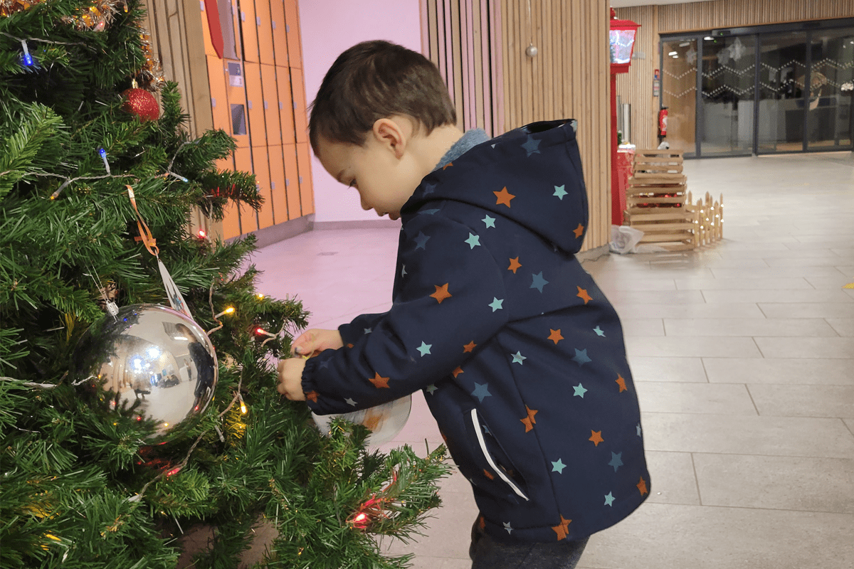 un enfant décore le sapin de Noël