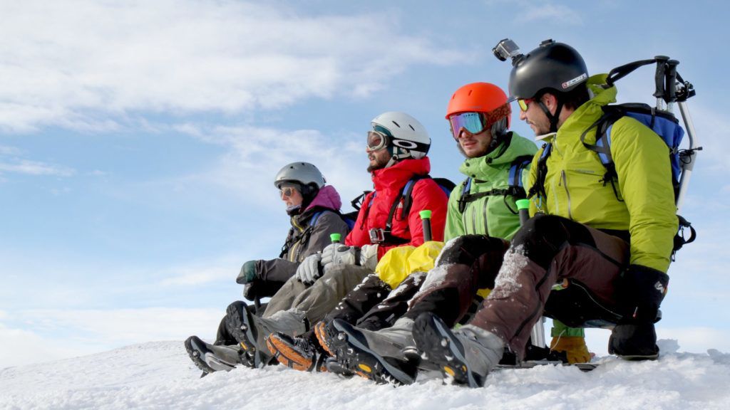 Des personnes en tenue de ski côte à côte sur des luges.