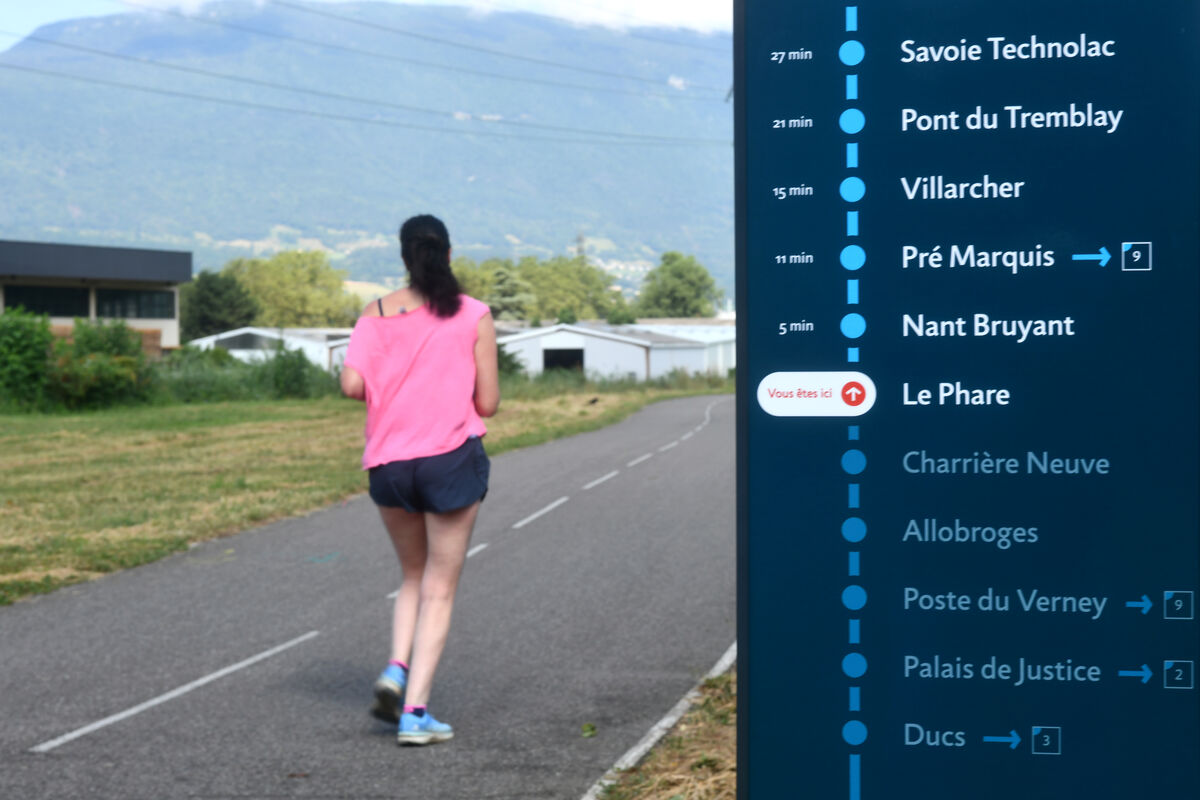 Sur une piste cyclable, une jeune femme se déplace en trottinette