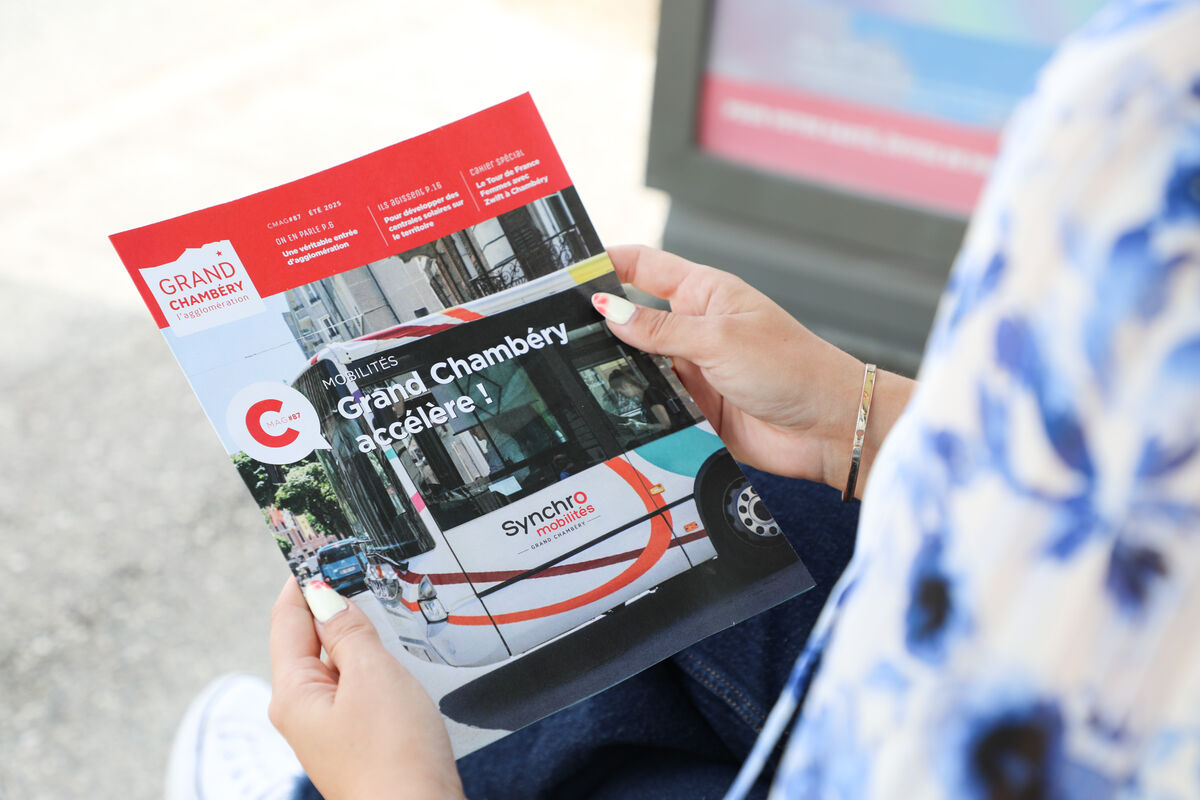 Une femme tient un magazine dans les mains à un arrêt de bus