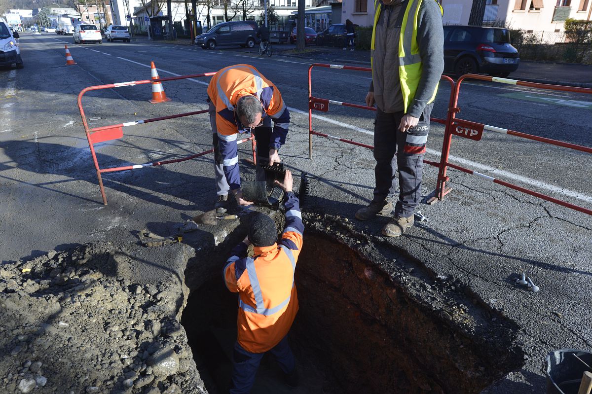 Des agents interviennent dans le trou d'une route pour réparer une fuite d'eau.