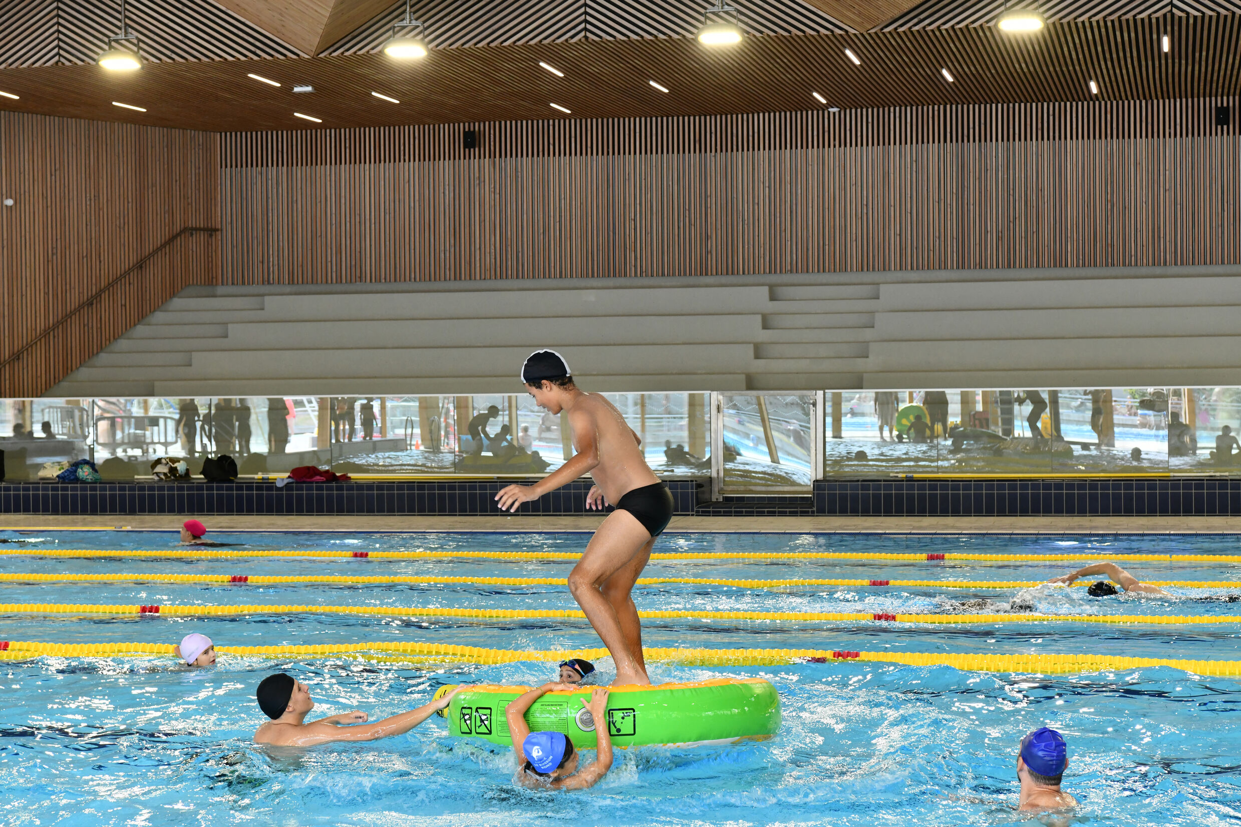 des enfants sont dans l'eau et sur des structures gonflables dans la piscine aqualudique du stade.  