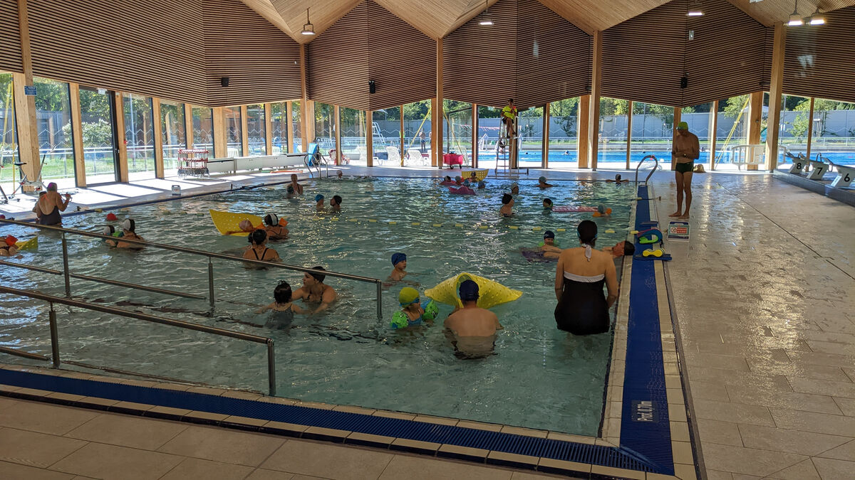 Des parents jouent avec leurs bébés dans une piscine publique.