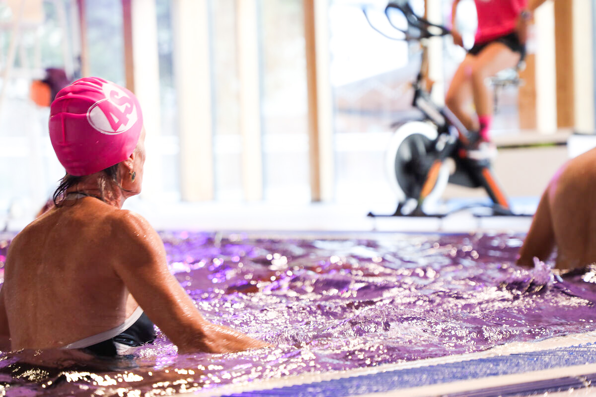Une femme dans l'eau participe à la soirée rose à la piscine aqualudique du stade